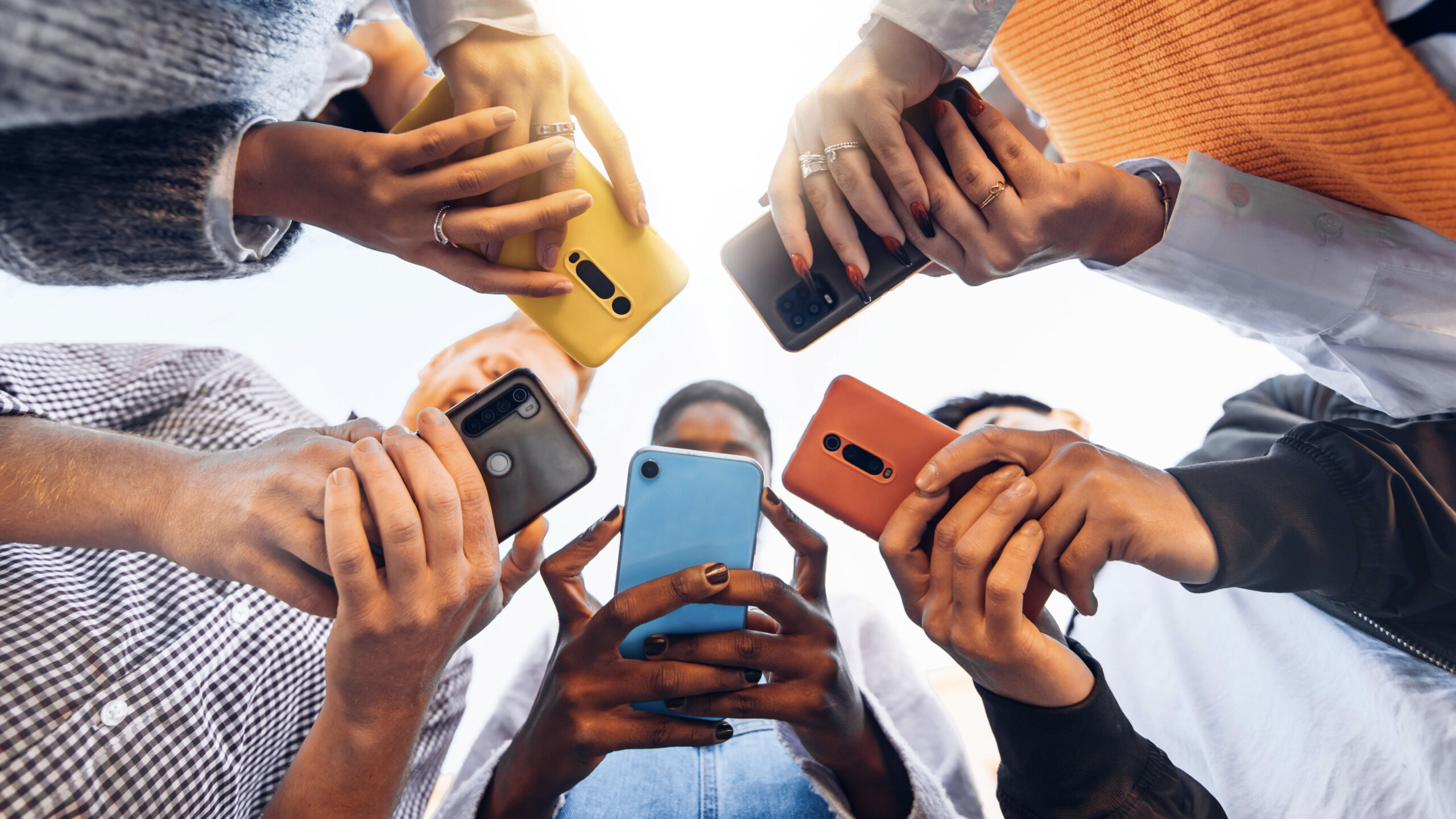 Teens in circle holding mobile phones