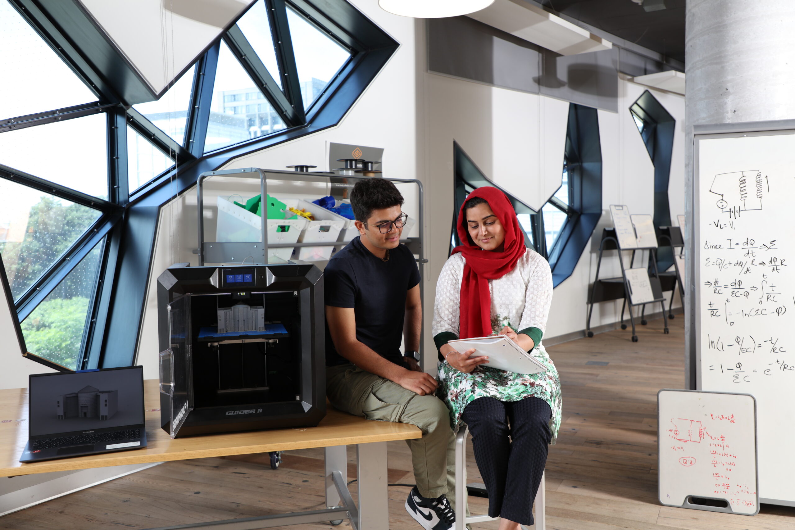 two students working with 3D model printer in Sandbox Lab