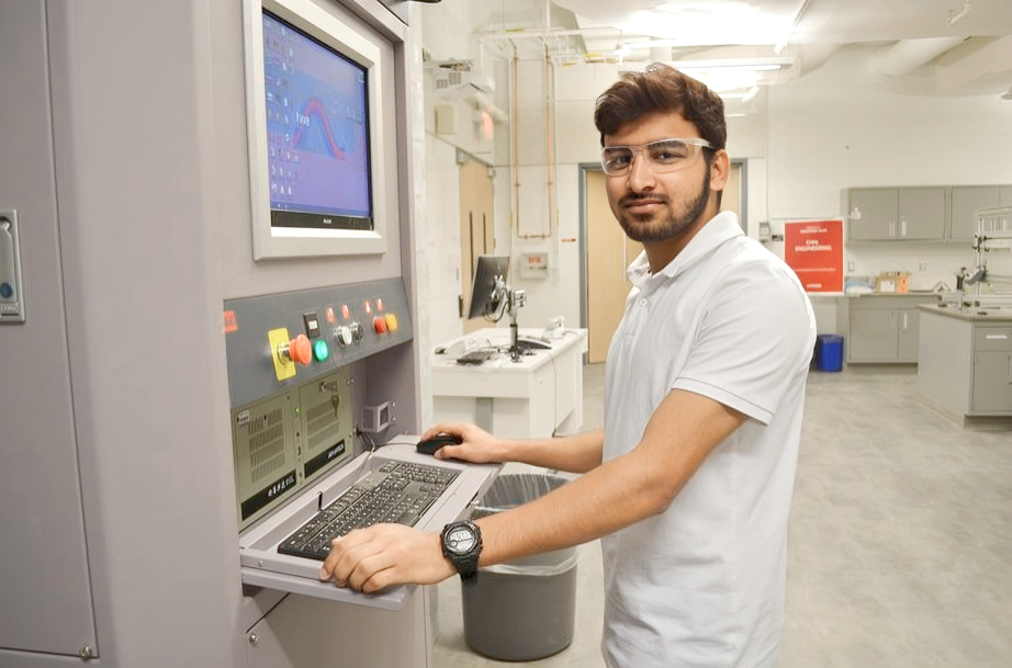 Lassonde Machine Shop, student standing at the machine controls looking at the camera