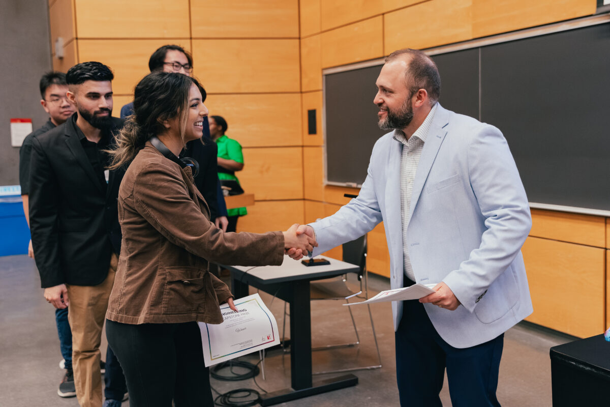 Mitch Burnie, Assistant Dean, Students shaking hands with a female capstone student