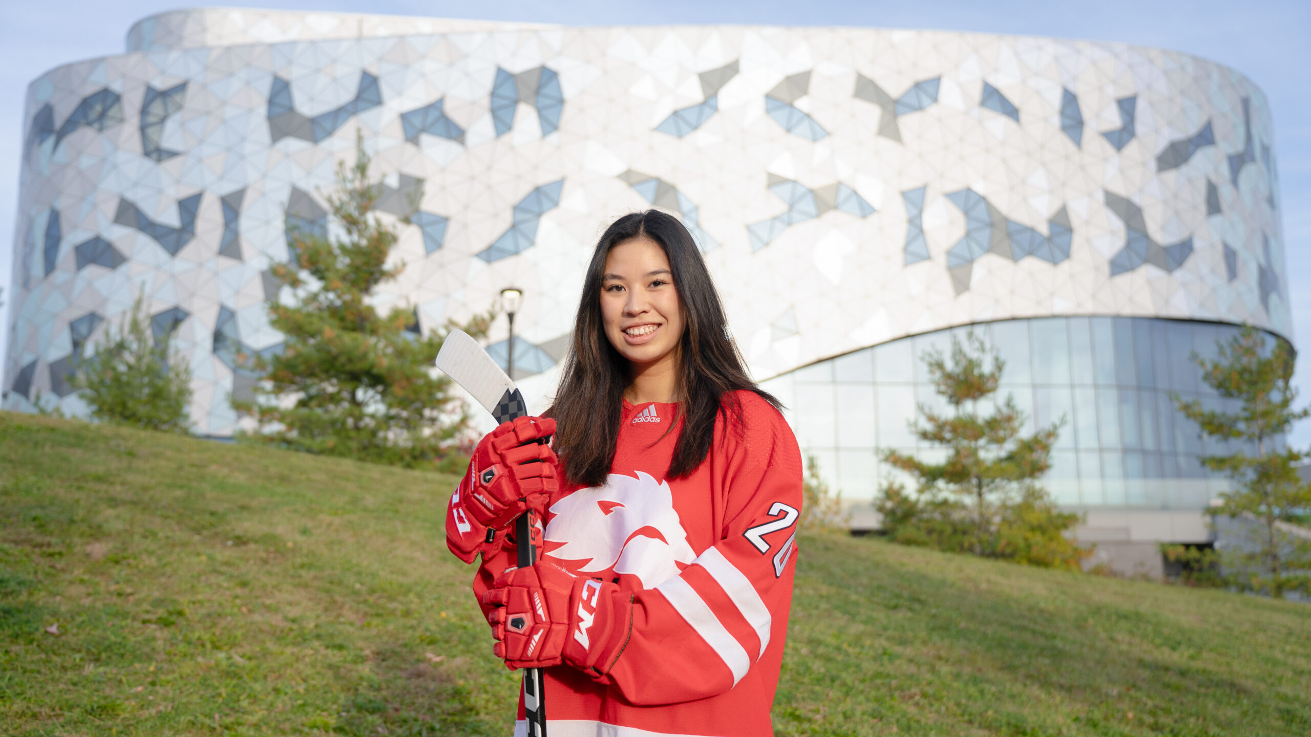 Abbey McMillan standing in front of the Bergeron Centre wearing her hockey uniform