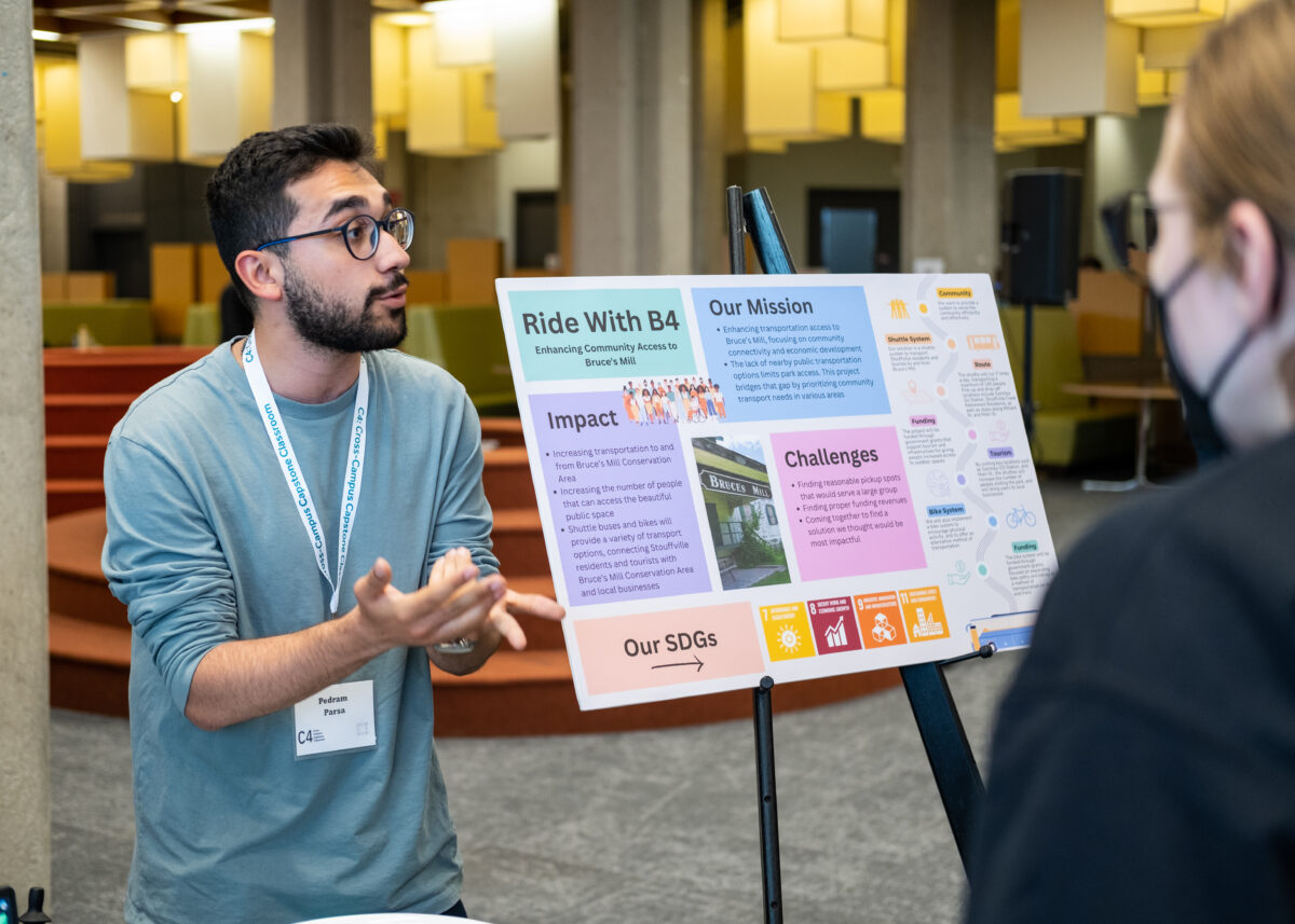 Male student standing next to a poster board presenting his work