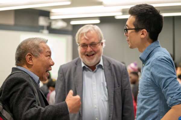 Dr. Benton Leong and Dr. Andrew Maxwell with a student smiling and talking