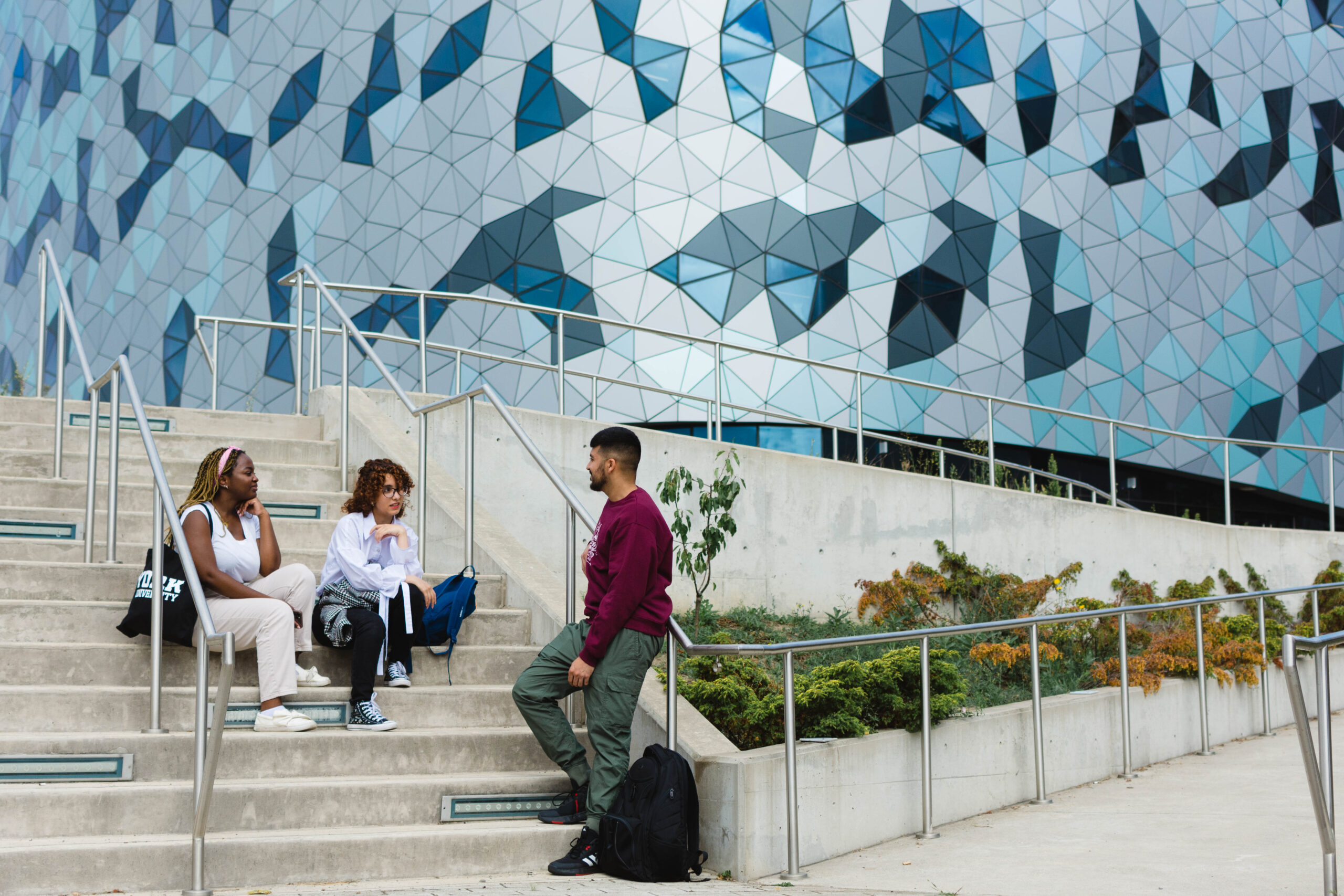 Trois étudiants de Lassonde discutent dans l'escalier à l'extérieur du Centre Bergeron.