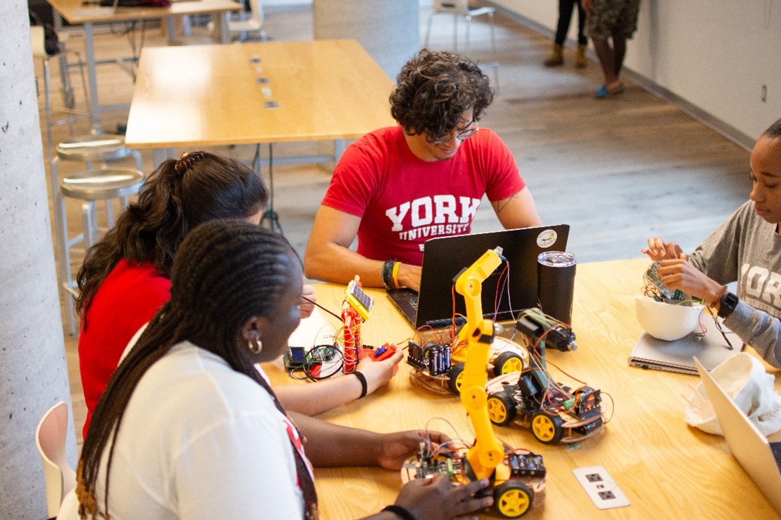 Students sitting at a table, tinckering with mini construction vehicle toys