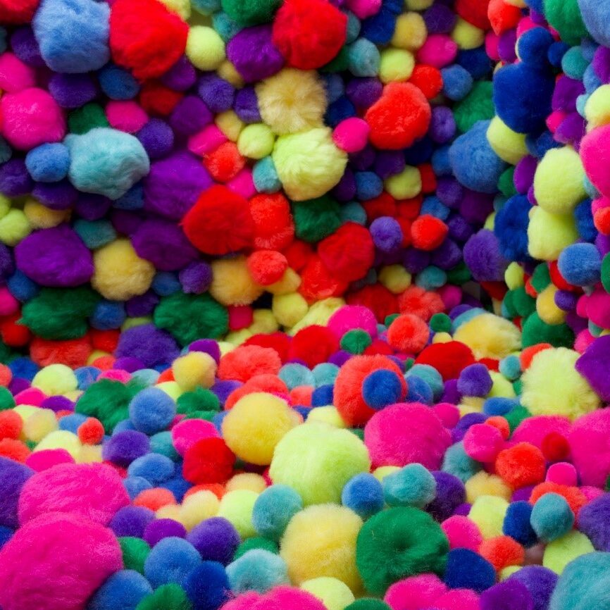 a bunch of multi-colored felt spheres (Loraxes) in a light box