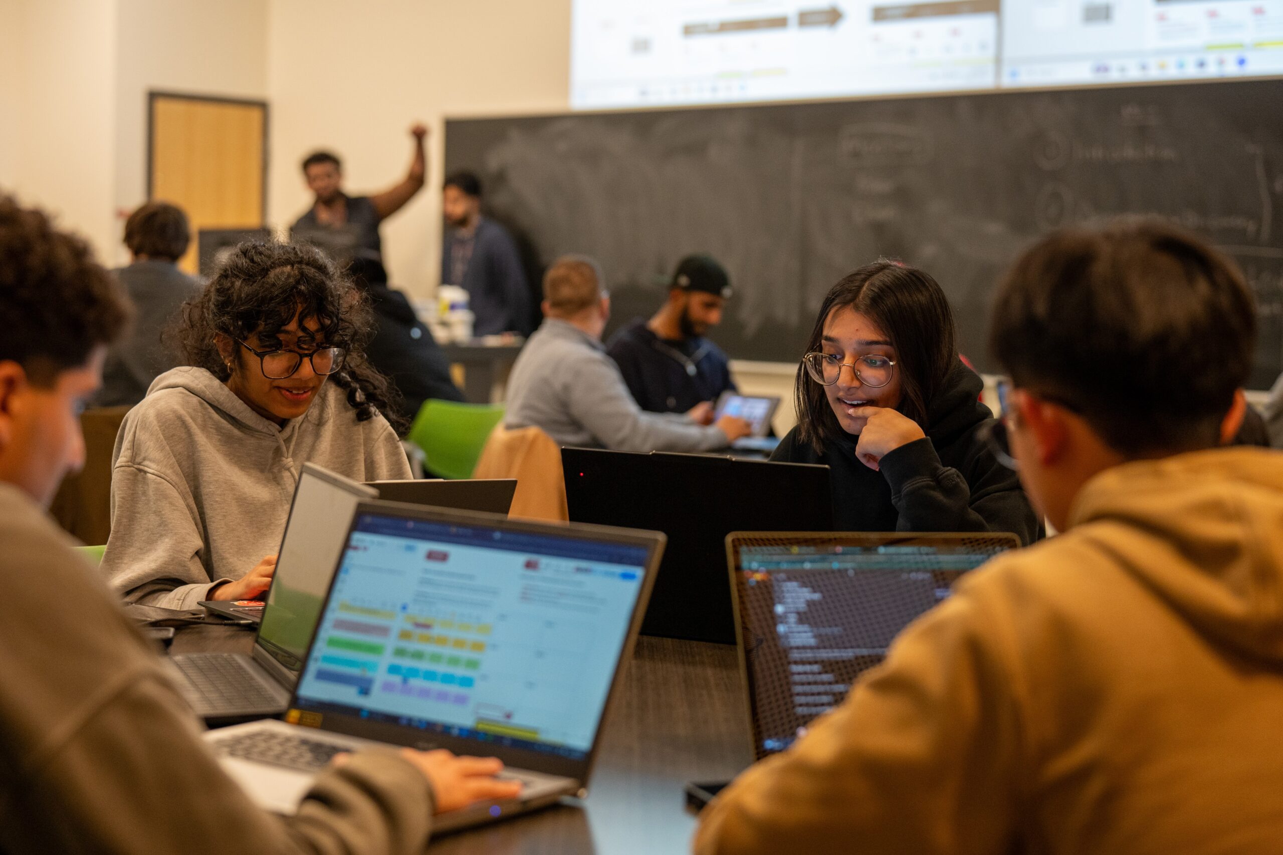 Students participating in the 2025 UNHACK. Image show students sitting together with coding programs open.