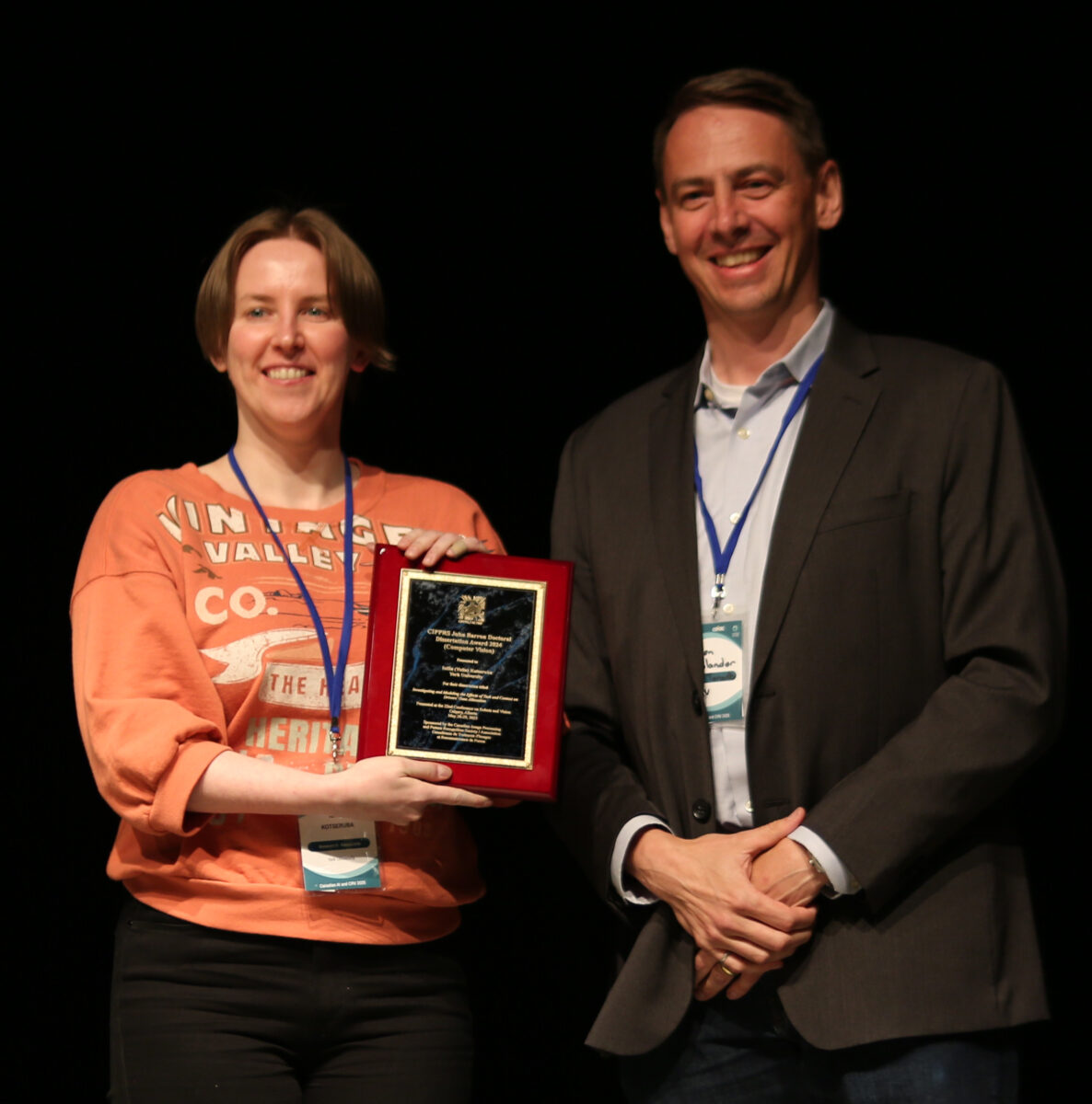 Iuliia hold an award next to a person.