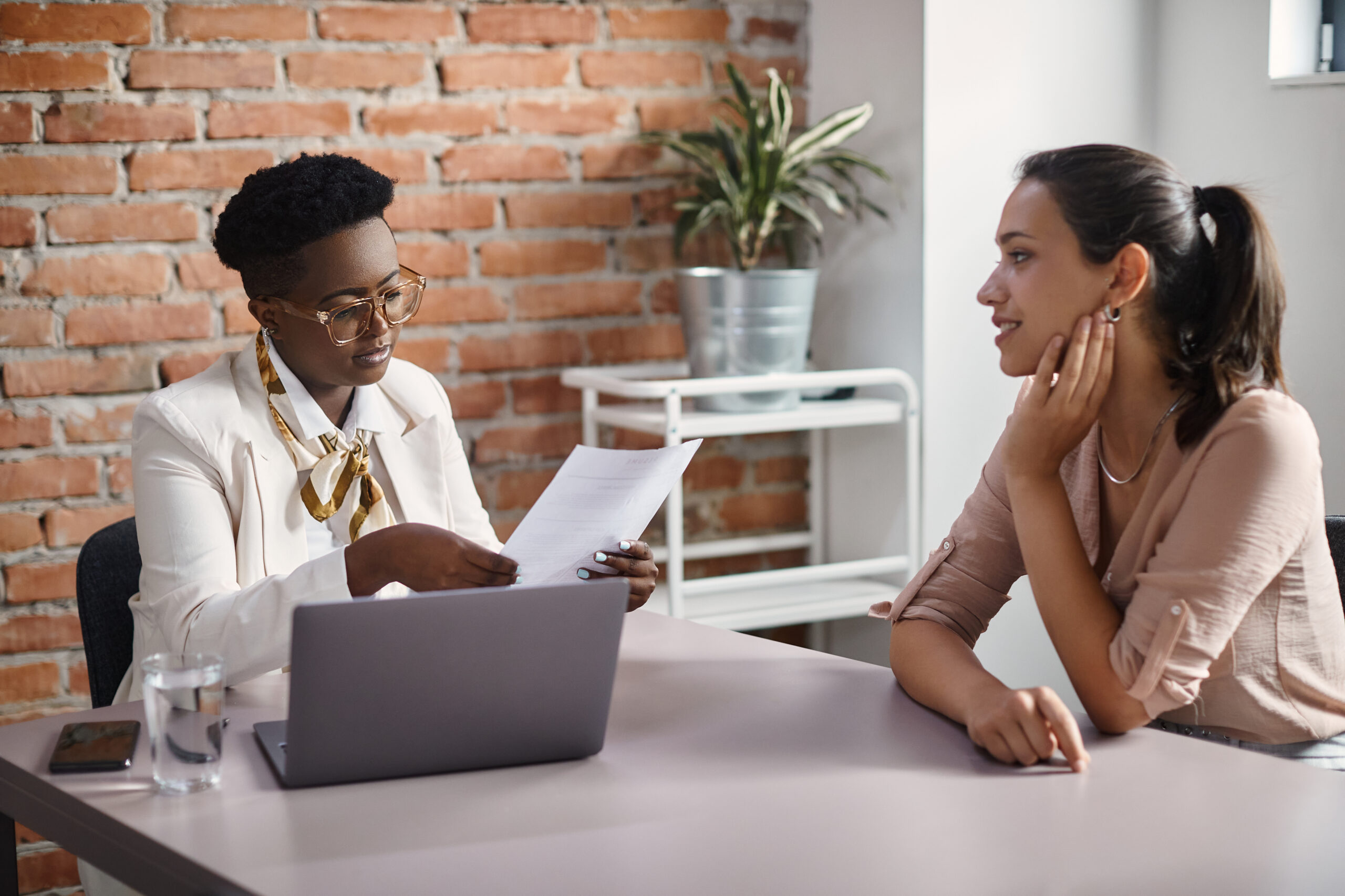 A manager talking to job candidate while reading her CV during a meeting in the office.