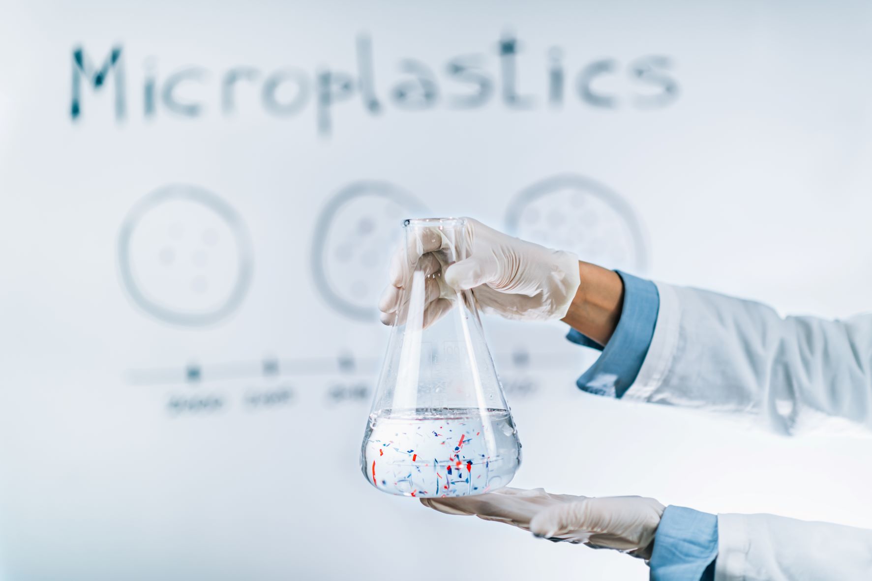 Microplastic pollution concept. Scientist holding a flask with a water sample full of tiny plastic particles.