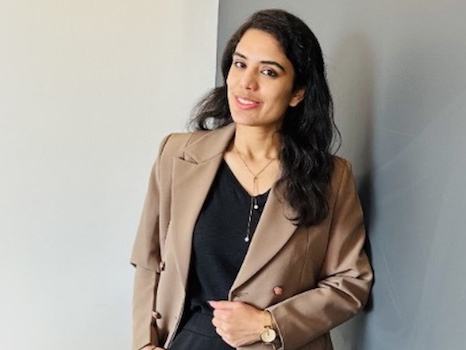 a woman in a brown blazer smiling at the camera