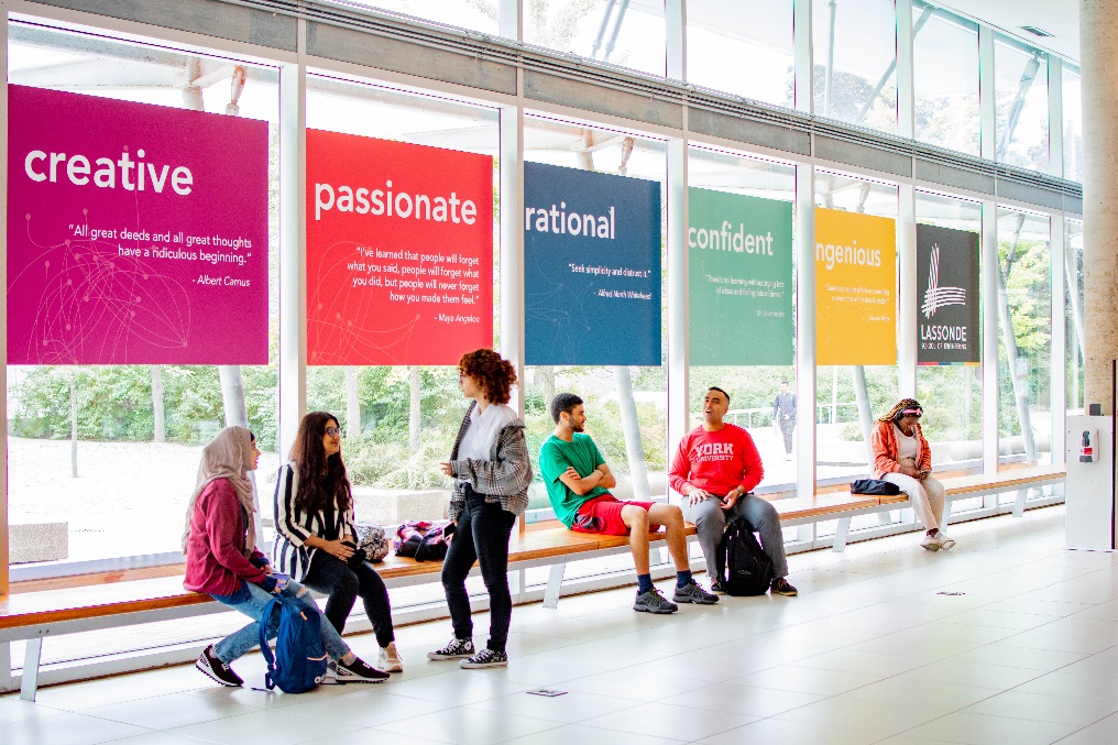 A group of students standing infront of colourful signs