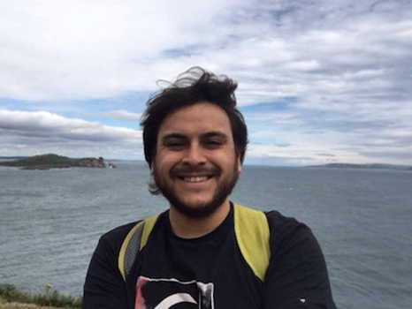 A man standing in front of a lake smiling at the camera