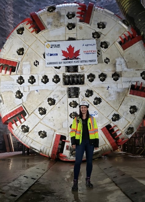 Josephine standing in front of a Tunnel Boring Machine (TBM) cutter head at the start of a tunnel project. 