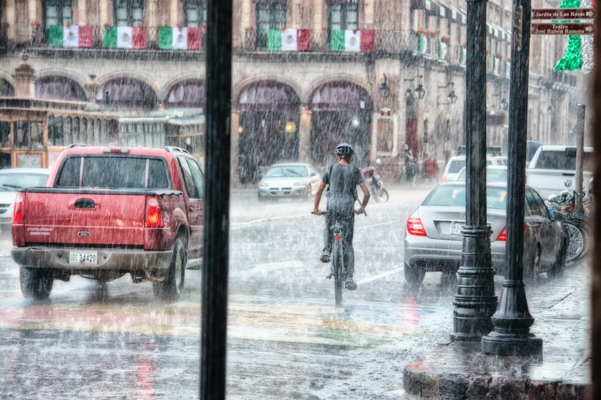 Vehicles travel down city road in rain