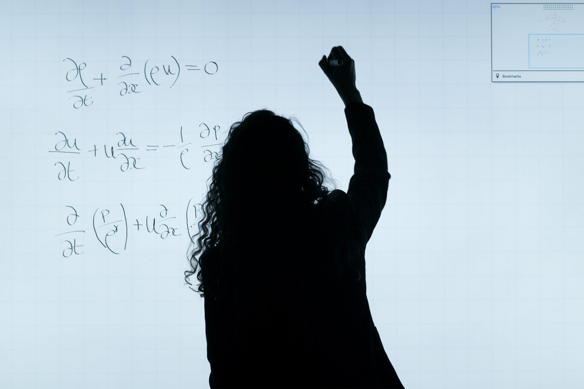 Person writes equations on blackboard